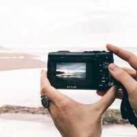 Person recording lake scenery with recording camera