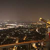 Kid in Paris looking through a telescope at night