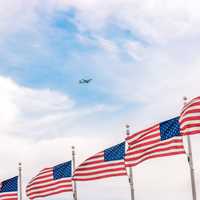 Plane flying above a bunch of USA Flags