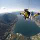 People skydiving above a lake