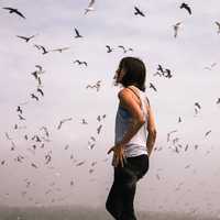 woman-standing-under-flying-flock-of-birds