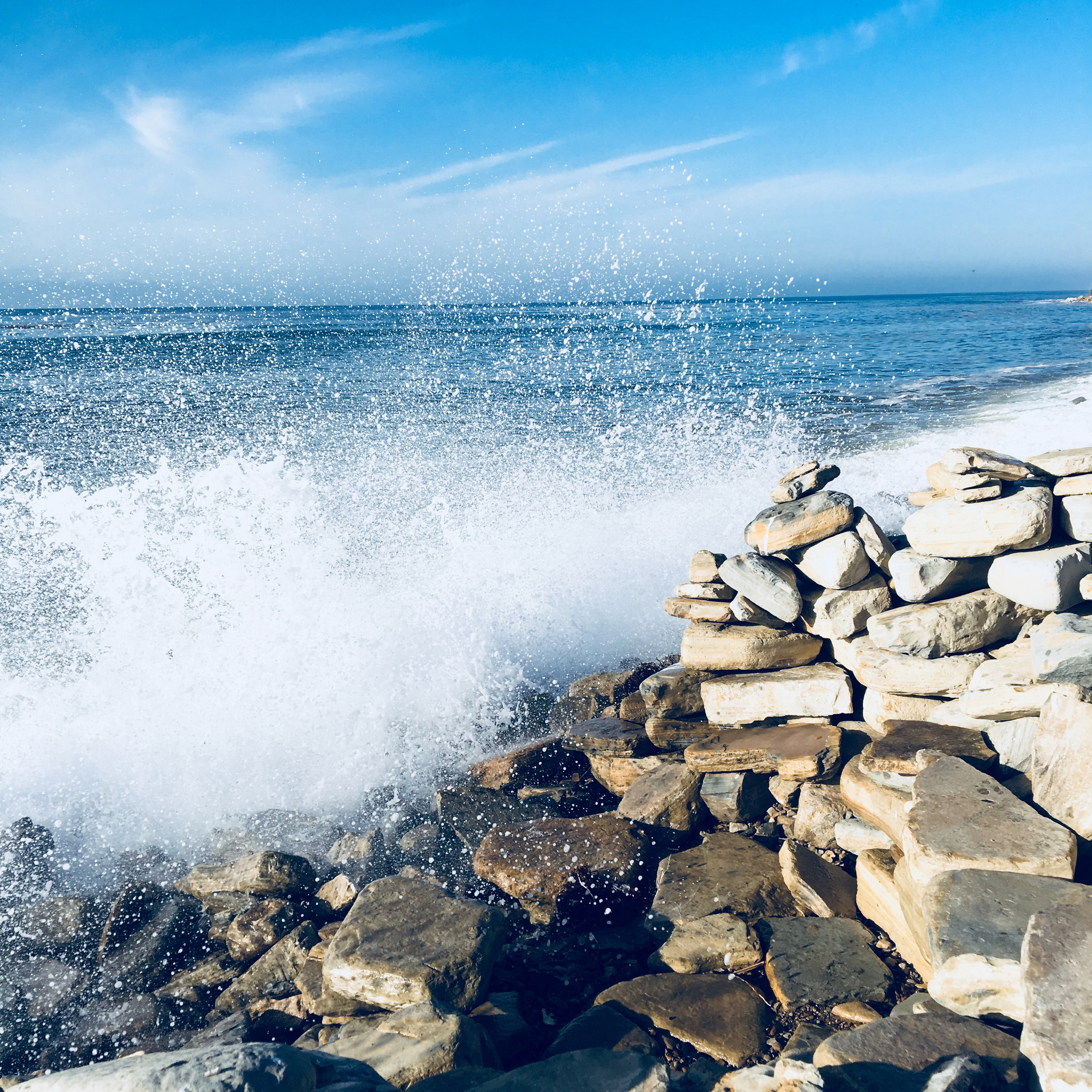 sea with big waves crashing to shore and rocks