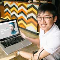 Asian Man smiling with a mockup on a macbook