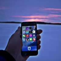 Hand holding phone at snowy sunset