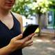 Woman in black tanktop holding black smartphone