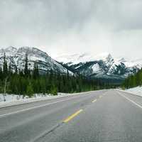 Road with snow-capped mountains with trees and landscape in Jasper National Park, Alberta, Canada