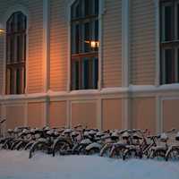 Snowy bicycles in front of library of architecture of Oulu University in Finland