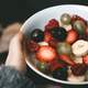 Hand holding a bowl of fruit