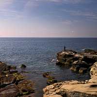 Person fishing on the cliffs near the ocean