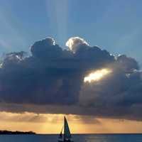 Sailboat under a clump of clouds at sunset in Jamaica