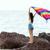 Girl standing on a rock with blanket on the seashore in the Maldives