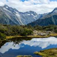 Milford Sound with mountains and reflective lake and clouds