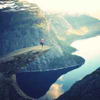 Women doing yoga overlooking the fjord in Trolltunga, Norway