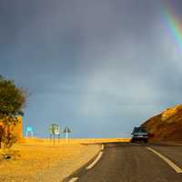 Car Driving into the landscape with a rainbow