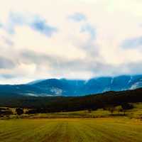 Fields and Mountains with white clouds in the sky