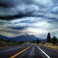 Highway Road into the mountains under heavy clouds