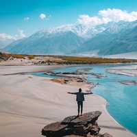 Man standing on a rock overlooking river and landscsape