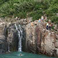 People swimming under the waterfall