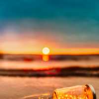 Bottle with ship on the beach at sunset