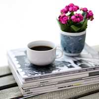 Coffee and flowers sitting on a stack of books