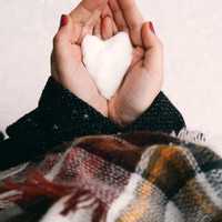 Hand holding White Snow in Heart shape