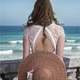 back-of-woman-in-dress-and-hat-looking-at-the-ocean