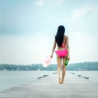 back-of-woman-wearing-pink-bathing-suit-walking-down-wooden-dock