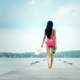 back-of-woman-wearing-pink-bathing-suit-walking-down-wooden-dock