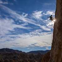 climber-on-a-rock-with-sun-shining-between-legs