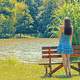 girl-in-blue-dress-standing-by-a-bench-by-a-lake
