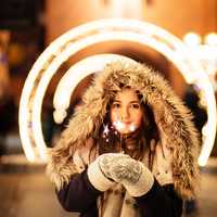girl-with-sparkler-with-lights-swirl-in-background-in-heavy-coats