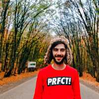 man-in-red-shirt-standing-in-a-corridor-of-trees