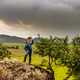 Man standing on top of a high rock under clouds