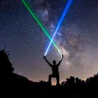 man-wielding-blue-and-green-lightsabers-in-the-starry-night-sky