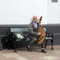 old-man-sitting-on-bench-playing-instrument