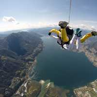 People skydiving above a lake