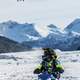 person-riding-snowmobile-with-mountains-in-the-background