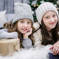 two-girls-sitting-next-to-christmas-tree-and-presents