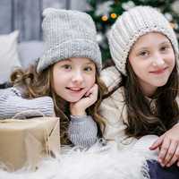 two-girls-sitting-next-to-christmas-tree-and-presents