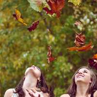 two-girls-throwing-leaves-into-the-air