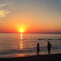 Two people watching sunrise over the ocean