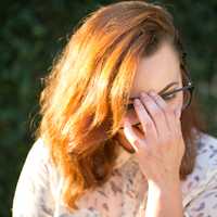 woman-holding-her-glasses-in-her-face