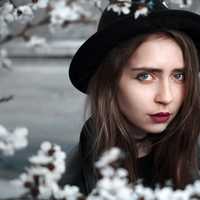 woman-in-black-clothes-and-hat-surrounded-by-white-flowers