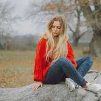 woman-in-red-sweater-sitting-on-log