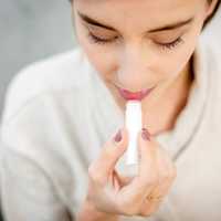 woman-in-white-shirt-putting-on-lipstick