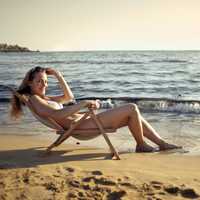 woman-sitting-on-the-beach-in-a-bikini-in-lawnchair