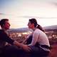 young-couple-sitting-together-on-a-hill-overlooking-a-town