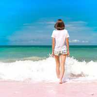 Young woman haveing fun with ocean waves on a tropical beach of