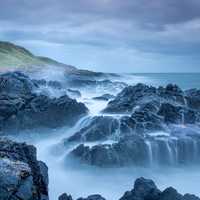 Lighthouse, rocks, waves, and ocean on a stormy day