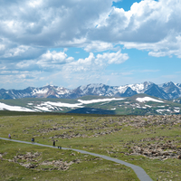 Snowy mountain peaks and people walking away from rock cut